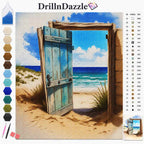 A completed cross-stitch or needlework artwork showing an open weathered blue door framing a beach and ocean scene, with the DrillnDazzle brand name at the top and a color reference chart on the right side.