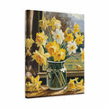 A square canvas wall art print depicting a bouquet of yellow and white daffodils in a clear glass vase on a windowsill, shown at an angle against a plain white background.