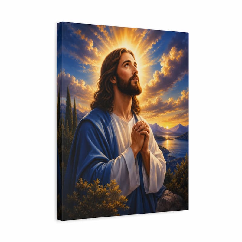 A vertical canvas wall art print depicting Jesus in a blue robe and white tunic praying with hands clasped, set against a dramatic sky with golden sun rays, clouds, mountains, and water.