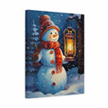 A square canvas wall art print depicting a winter snowman scene. The snowman wears a red hat and scarf, holding a glowing lantern, set against a snowy landscape with pine trees under a dark blue night sky.