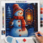 A diamond painting kit sheet featuring a winter snowman holding a glowing lantern, shown with a color list, paint pots, tools, and a hand holding a paint pen on a light marble surface.