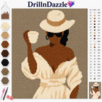 A diamond painting or cross-stitch style craft kit cover showing a woman in a white hat and dress holding a cup, with the brand name DrillnDazzle at the top. The left side shows color beads/pastels, and the right side shows a numbered color chart.