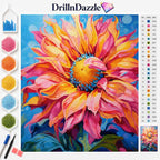 A colorful diamond painting or cross-stitch style floral design featuring a large sunflower with pink, orange, yellow, and blue tones. The image includes the brand name DrillinDazzle at the top, a color chart on the right, a small finished preview in the lower right, and paintbrushes/paint pots on the left against a white background.