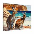 A square canvas wall art print depicting two brown kangaroos on a sandy beach with turquoise water and orange rock cliffs in the background, shown at a slight angle against a white studio backdrop.