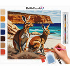 DrillnDazzle diamond painting kit featuring a kangaroo and wallaby painting design, with a color list chart, paint swatches, and a hand holding a pink paint pen on a white background.