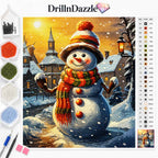 DrillnDazzle diamond painting kit featuring a winter snowman design. The image shows the completed painted canvas in the center, with beads in multiple colors, two metal needles, and a color reference chart on the left and right margins, all set against a clean white background.