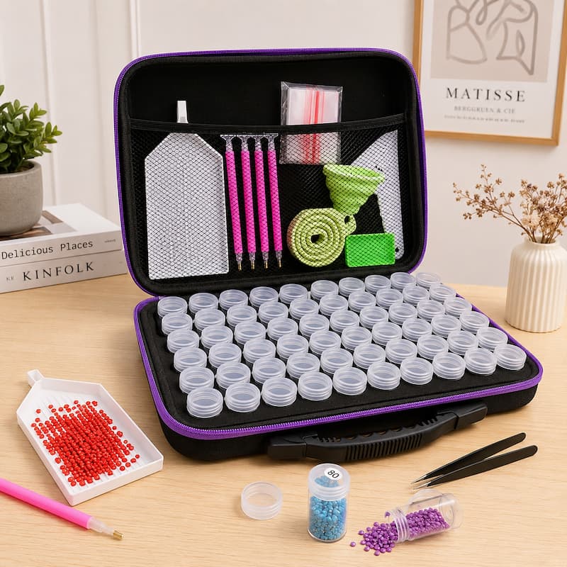 An open black and purple jewelry making kit organizer on a wooden table, filled with small plastic vials, mesh pouches, pencils, and tools. Surrounding items include red, blue, and purple beads, tweezers, a pink pen, and a small scoop of red beads.