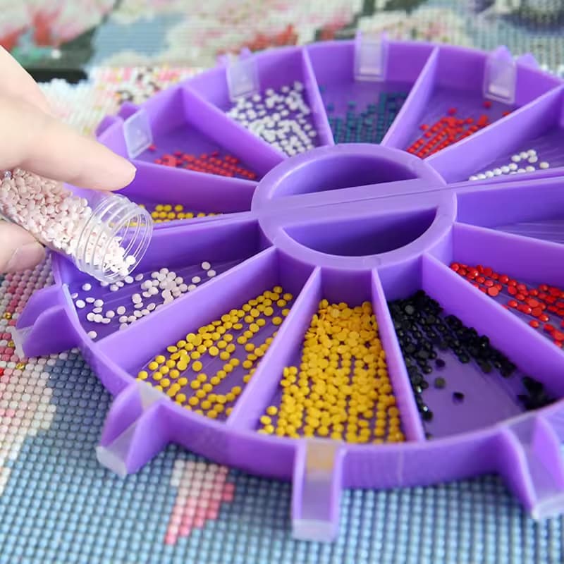 Purple organizer with compartments filled with small beads on a cross-stitch background