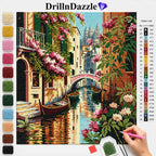 A diamond painting kit by DrillnDazzle showing a colorful canal scene with houses, boats, and pink flowers. The image includes a color list chart on the right and a vertical row of color swatches on the left.